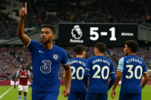 Chelsea players celebrate after a dominant 5-1 victory over West Ham at London Stadium, with João Pedro leading the celebration and the scoreboard showing the final score.
